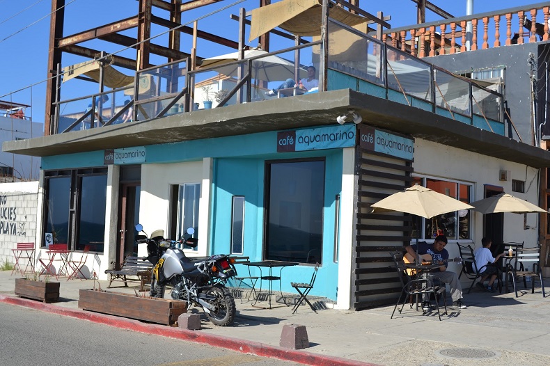 Fachada turquesa de Café Aquamarino con terraza y mesas exteriores