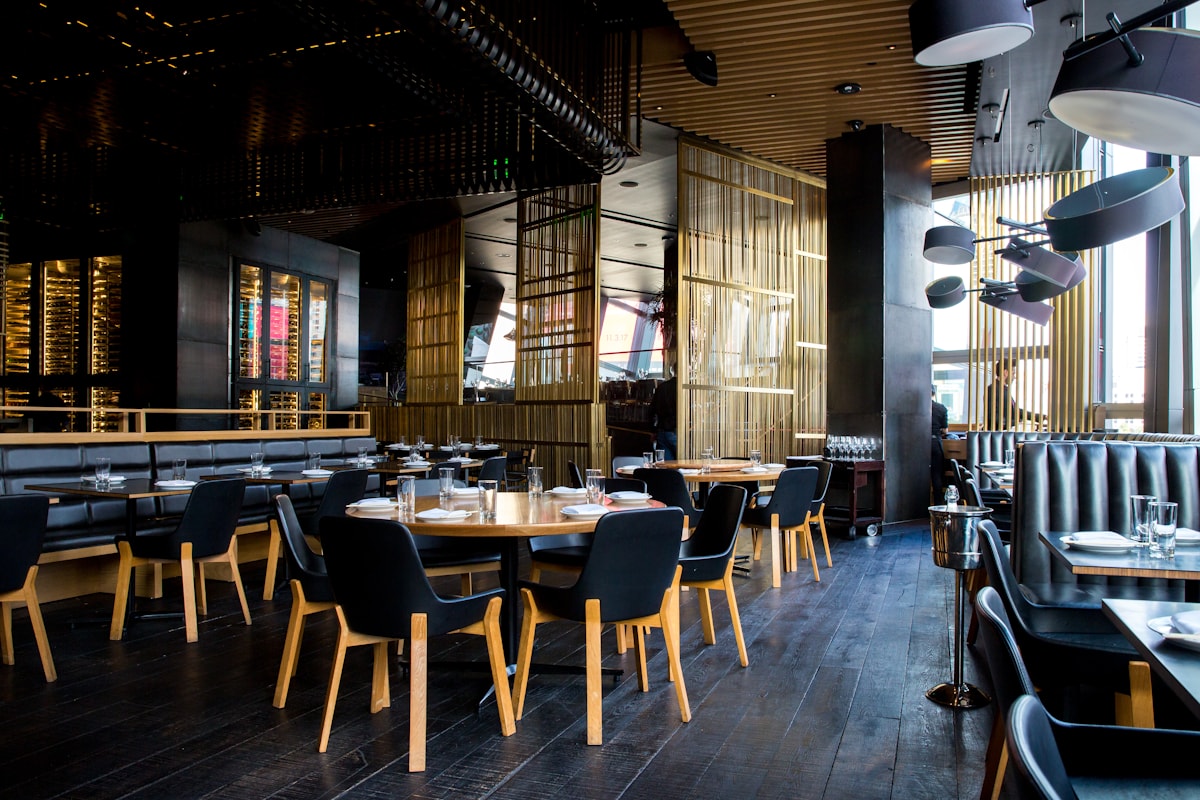 Imagen conceptual de un interior de restaurante con mesas, madera y luz cálida; no es una fotografía de Ophelia.