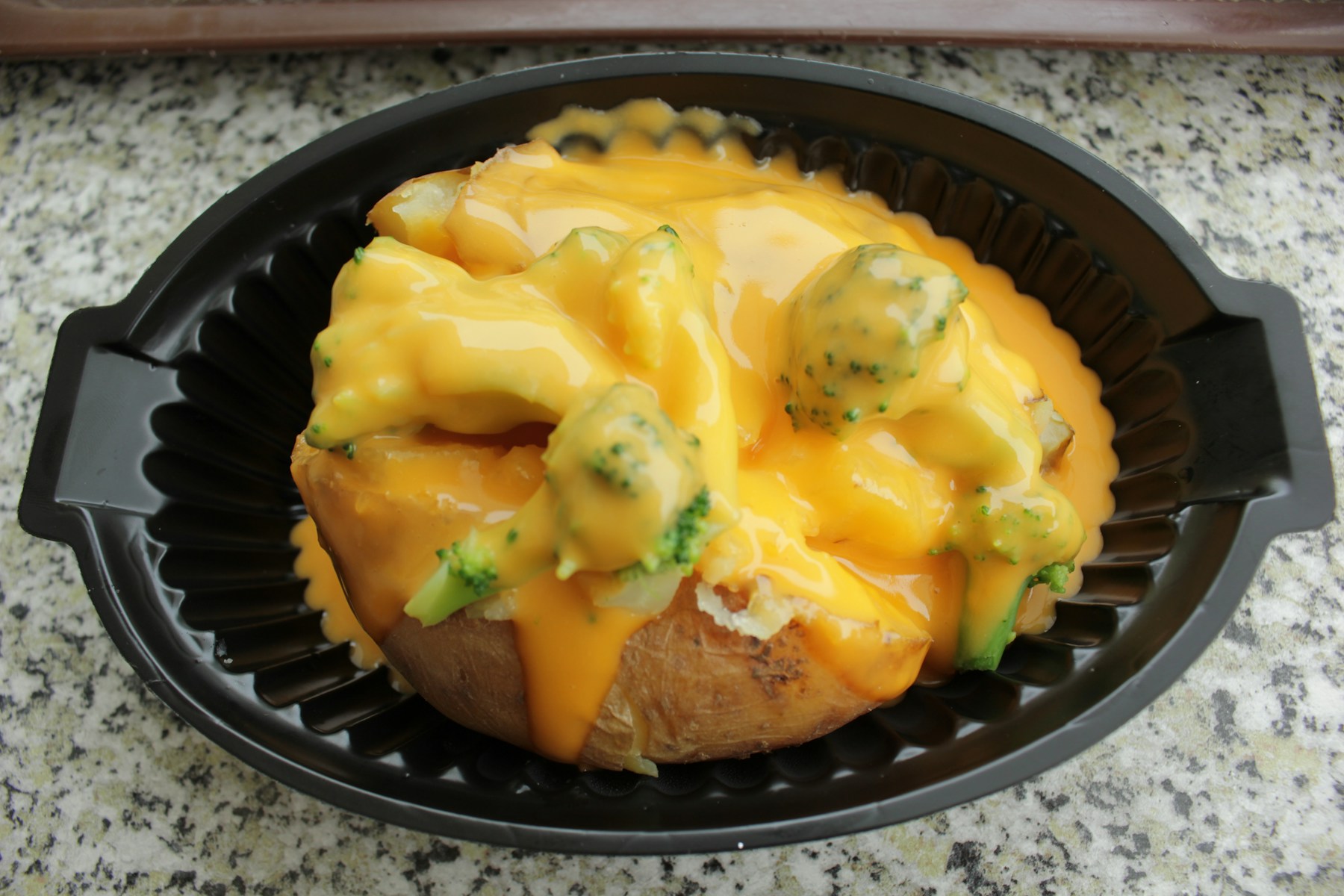 Imagen de referencia de una papa horneada abierta con queso y brócoli; no es una foto de Tío Papas